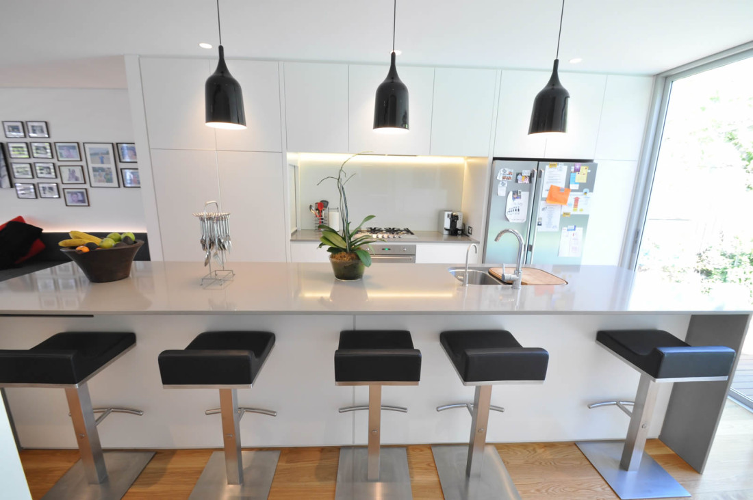 Carrington Kitchen with bar stools and hanging pendant lights. Grey stone benchtop