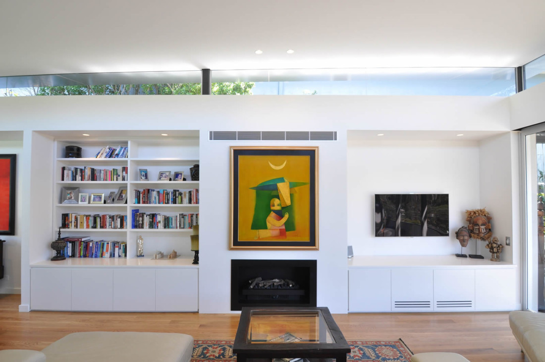 Carrington Living Room with artwork hanging above fireplace and wall mounted tv with integrated wall book shelves